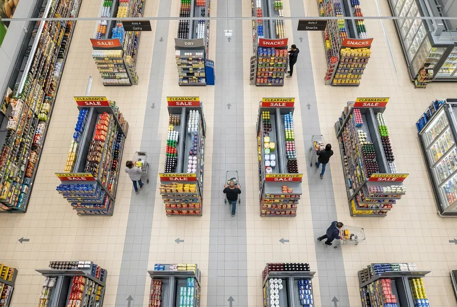 Vista aérea de corredores largos de supermercado com fluxos livres ao redor das ilhas promocionais temporárias.