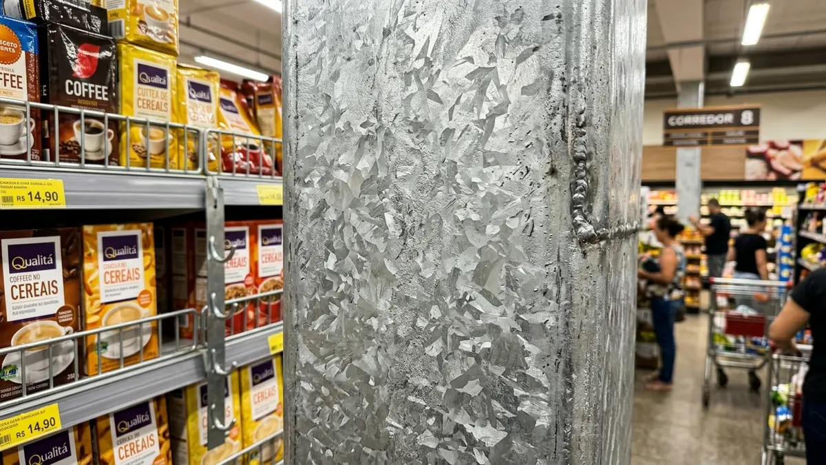 Chapa de aço galvanizada a fogo brilhante em coluna de gôndola e etiquetas de preço em português com marcas de alimentos brasileiros.